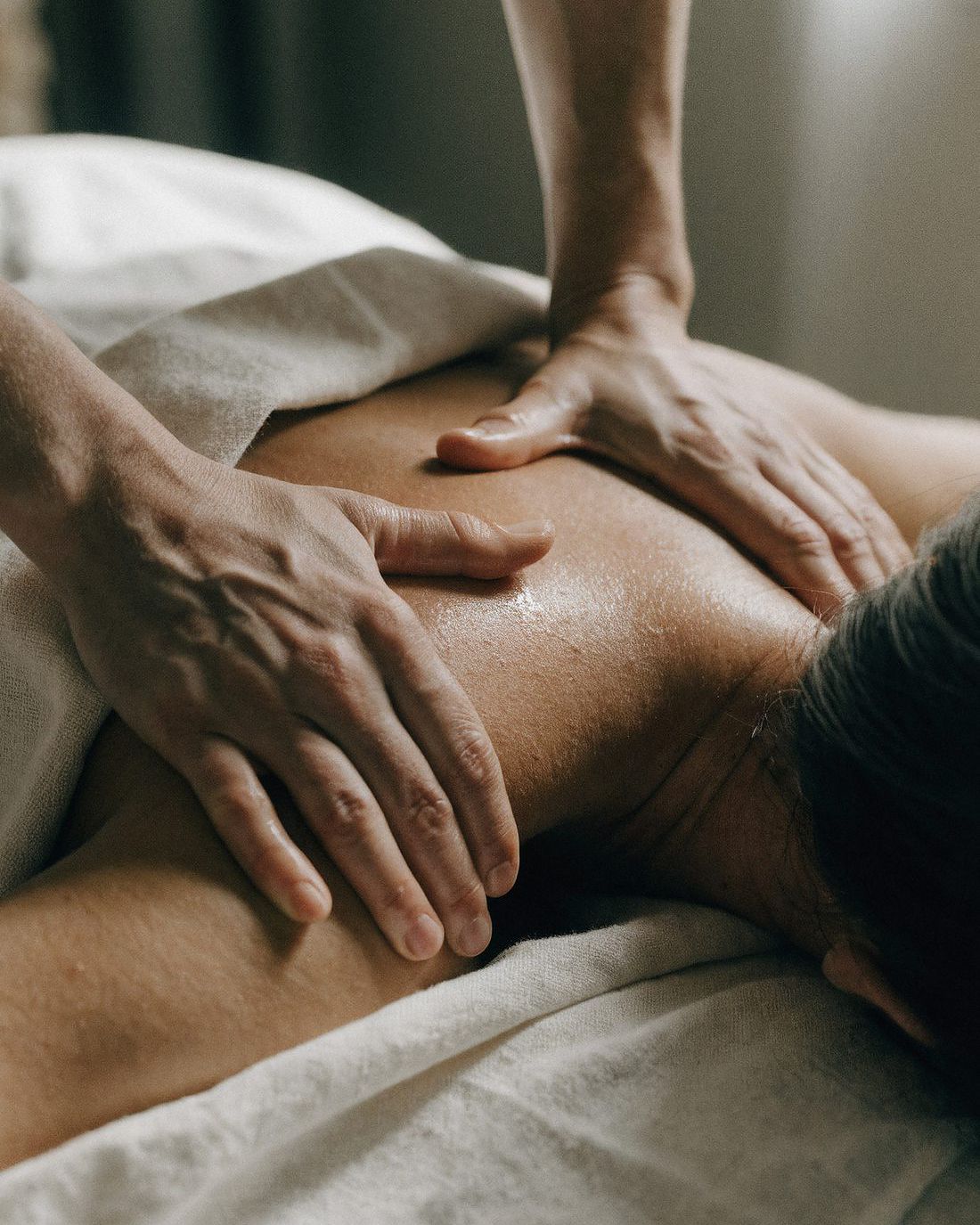 Massage von Schulter und oberem Rücken mit pflegendem Öl und Leinenabdeckung