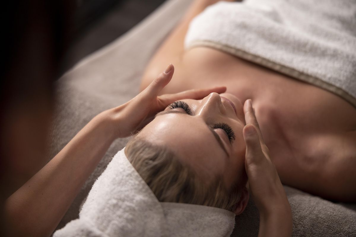 Gästin mit Handtuch im Haar erhält eine ruhige Gesichtsmassage