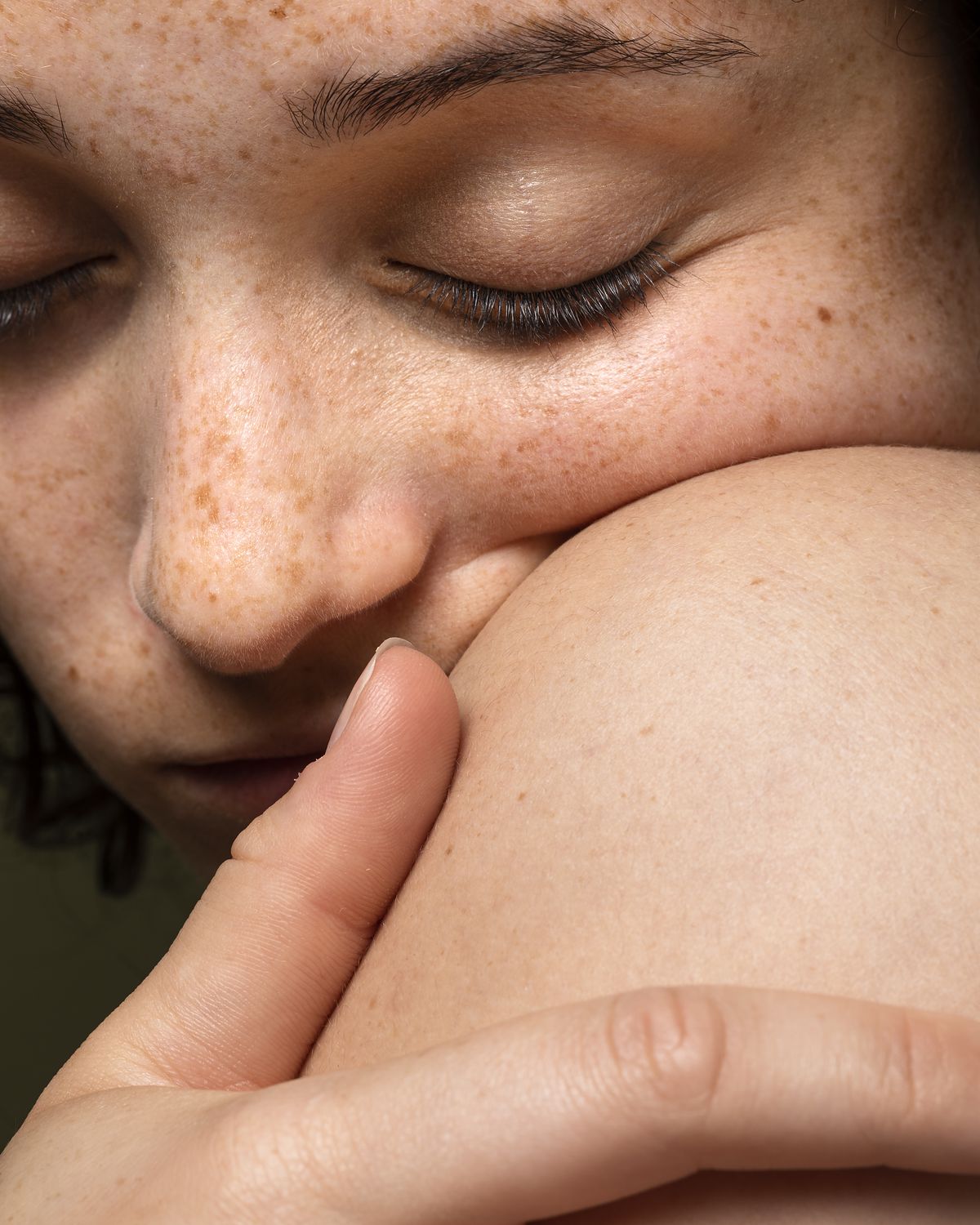 Ruhendes Gesicht, an die eigene Hand gelehnt, Augen geschlossen